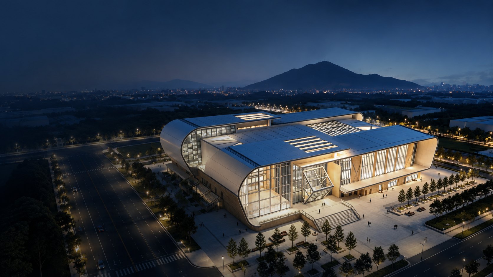 High-angle blue-hour view of Bay Arc Stadium, its illuminated entrance plaza and surrounding city